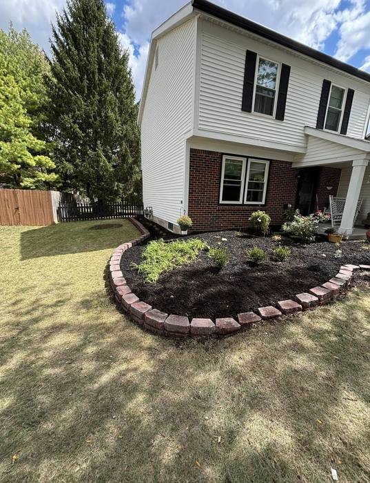 Bed with fresh mulch and decorative stone edging along a walkway